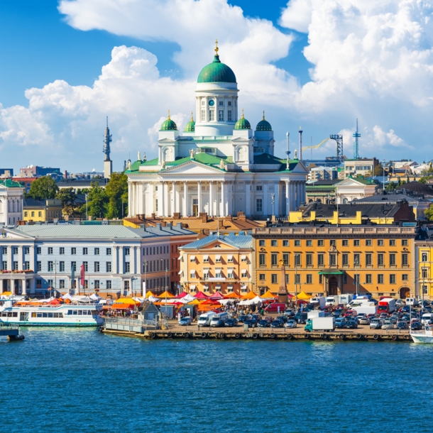 Blick auf eine Stadt am Wasser mit bunten Häusern und einer weißen Kathedrale im Mittelpunkt.