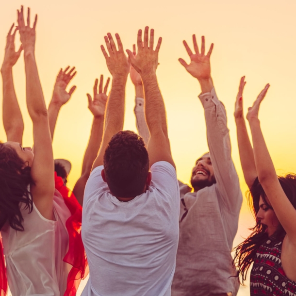 people dancing at the beach with hands up. concept about party, music and people