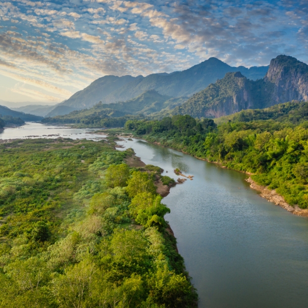 Flusslandschaft des Mekong in Laos mit Bergen im Hintergrund.