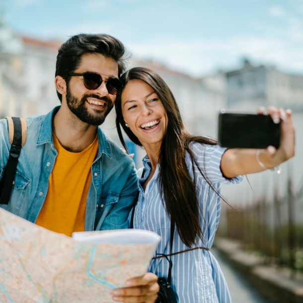 Ein fröhliches Paar mit Straßenplan beim Selfie fotografieren in urbaner Umgebung.