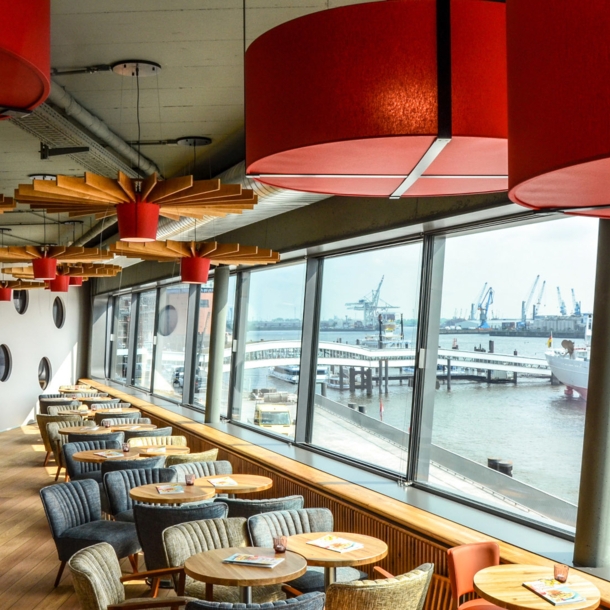 Modernes Bistro mit Blick auf den Hamburger Hafen durch Panoramafenster.