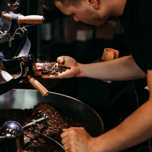 Ein Mann kontrolliert die Röstung von Kaffeebohnen