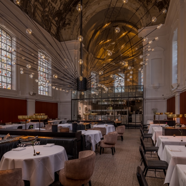 Edles Restaurant mit großem Deckenleuchter in einem Kirchengebäude.