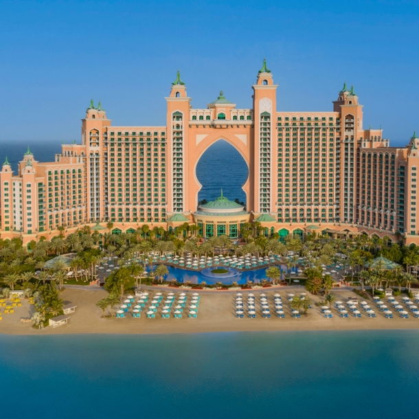 Großer Hotelkomplex im arabischen Stil auf einer Landzunge mit Sandstrand, umgeben von blauem Wasser.