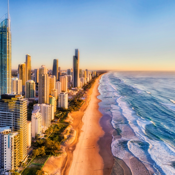 Luftaufnahme der Skyline von Surfers Paradise am kilometerlangen Sandstrand bei goldenem Sonnenlicht.