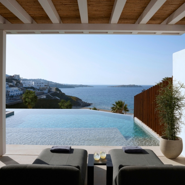 Terrasse mit Liegen und Infinitypool mit Meerblick an einem Küstenort.