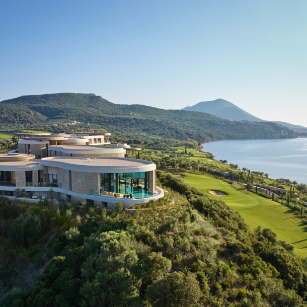 Hotelanlage inmitten einer grünen Hügellandschaft am Meer.