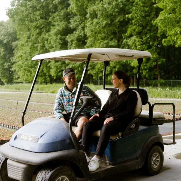 Die Gründerin Antonia Cox sitzt mit Benjamin Diedering in einem Golfplatzfahrzeug und stellt ihm ihr grünes Start-up vor