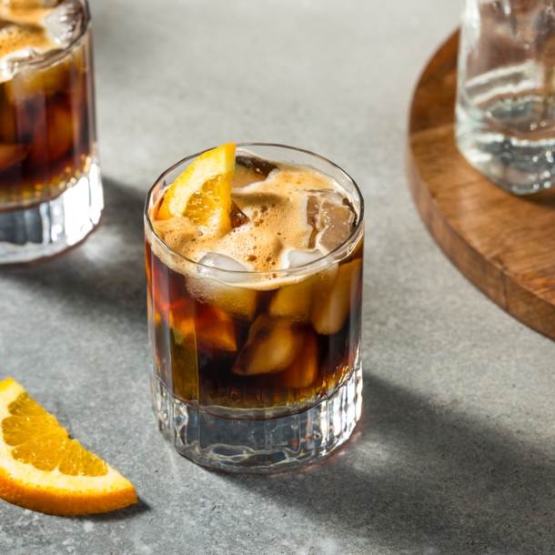 Zwei Gläser Espresso Tonic mit Eiswürfeln und Orangenscheiben.