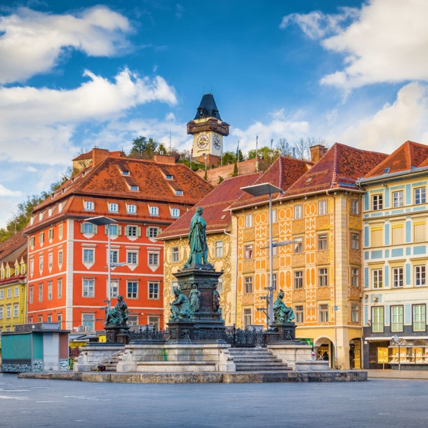 Marktplatz mit Brunnen vor bunter Häuserfassade in der Altstadt von Graz.