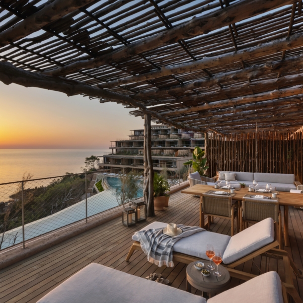 Luxuriöse Hotelterrasse mit Holzpergola am Meer bei Sonnenuntergang.