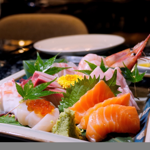 Verschiedene Sashimi Sushi und Scampi auf einem dekorierten Teller in einem Restaurant.