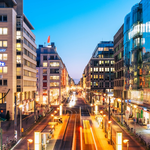 Einkaufsstraße im Stadtzentrum mit beleuchteten Gebäuden bei Abenddämmerung.