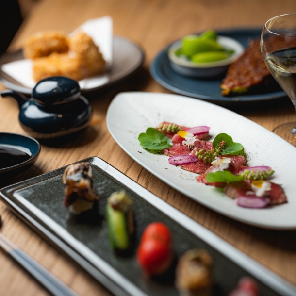 Gedeckter Holztisch mit japanischen Tapas und Sushi-Kreationen.