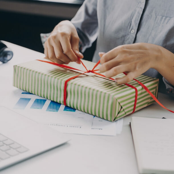 Frau am Arbeitsplatz verpackt ein Geschenk