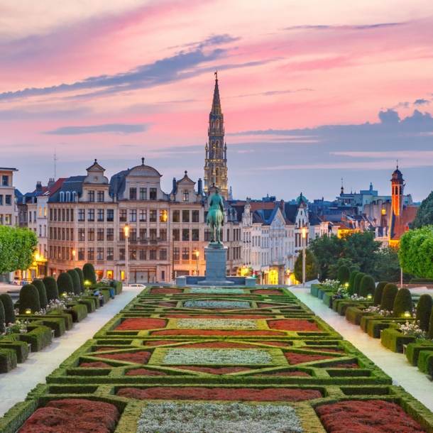 Skyline von Brüssel mit Parkanlage im Vordergrund bei Abenddämmerung unter rosagefärbtem Himmel.