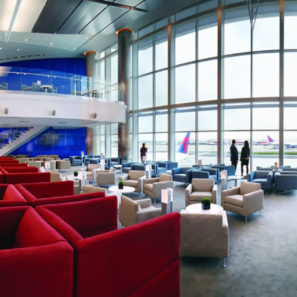 Geräumige Flughafen-Lounge in den Farben Rot, Weiß und Blau mit Blick aufs Rollfeld durch Panoramafenster.