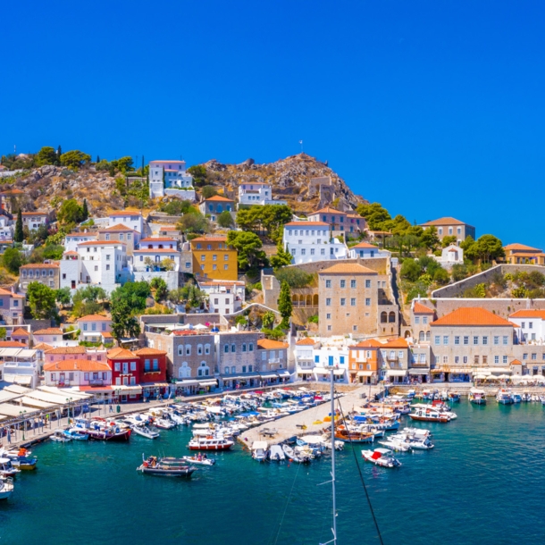 Mediterrane Ortschaft in Hanglage am Meer mit Hafenpromenade und Fischerbooten.