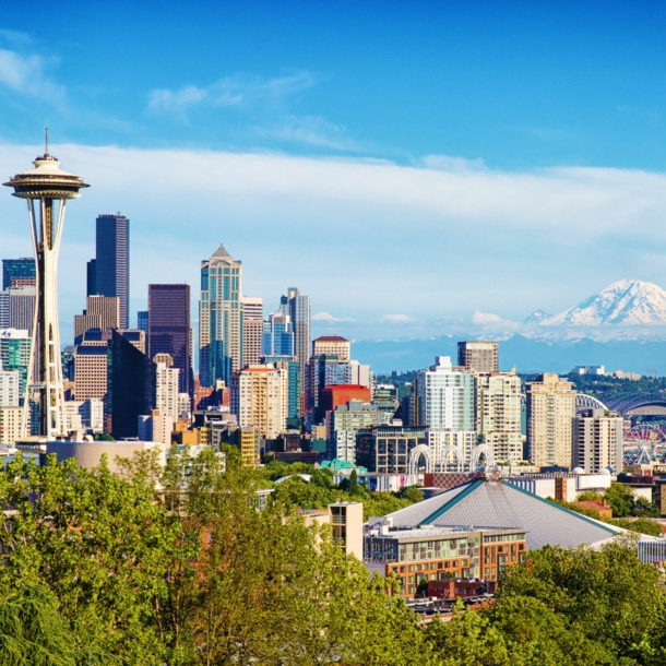 Skyline von Seattle mit Space Needle Turm vor schneebedeckter Bergspitze am Horizont.