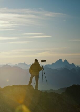 Ein Zelt und ein Mann mit Fotoapparat vor einer Hochgebirgskulisse