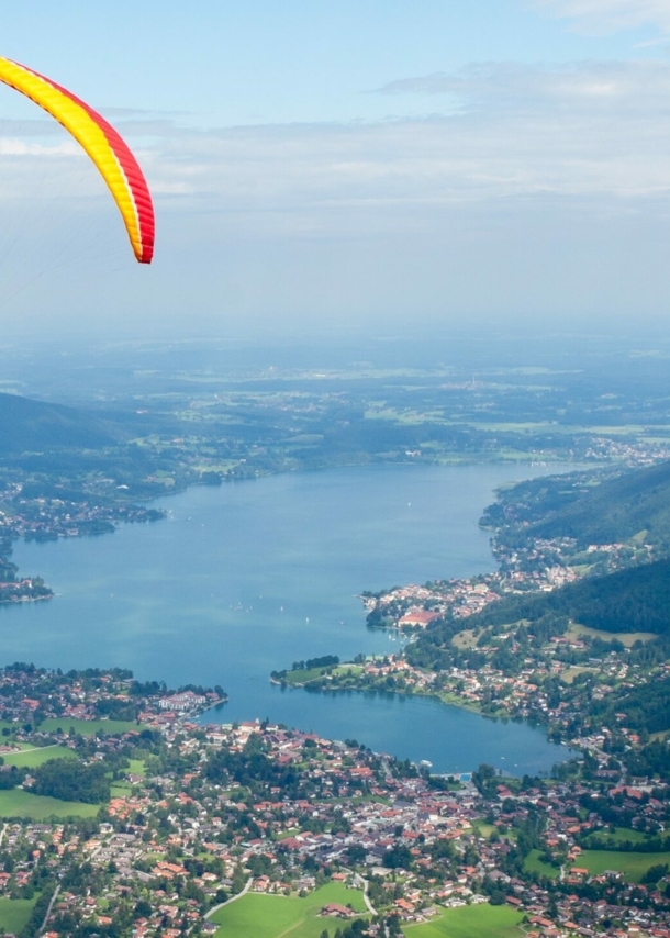 Gleitschirmflieger mit Blick von oben auf den Tegernsee