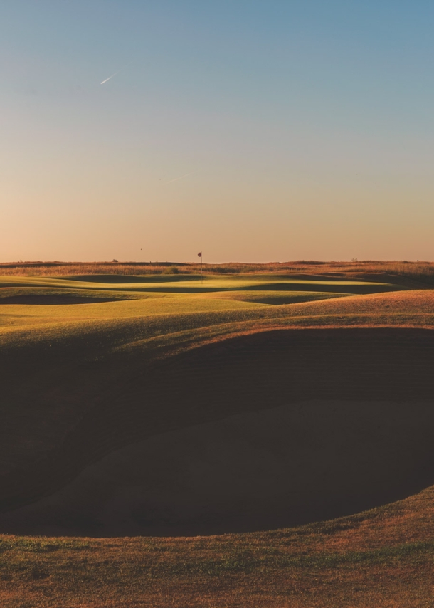 Surreal anmutende Graslandschaft mit großem Krater im Vordergrund