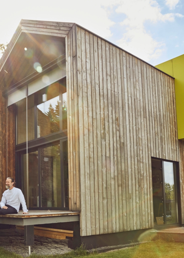 Ein Mann sitzt auf der Terrasse eines Tiny Houses