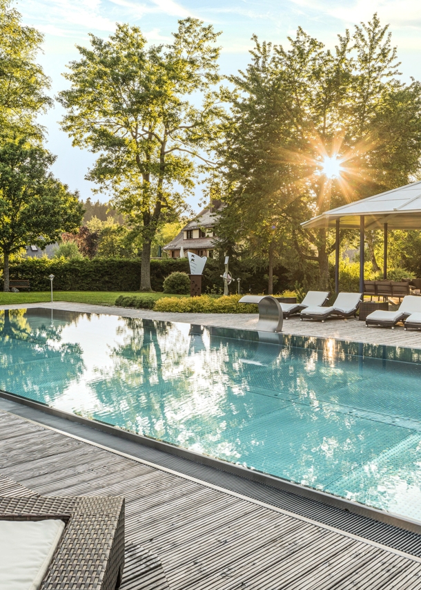 Elegante Terrasse mit Außenpool und Liegestühlen in begrünter Umgebung