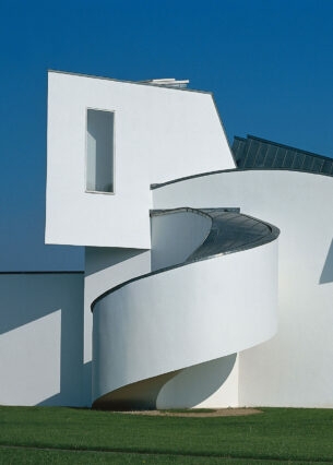 Ein weißes, architektonisch verspieltes Gebäude auf einer grünen Wiese.