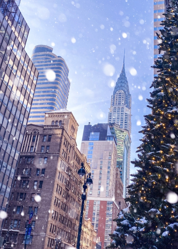 Häuserschlucht in Manhattan mit Blick auf Chrysler Building und Tannenbaum im Vordergrund bei Schneefall