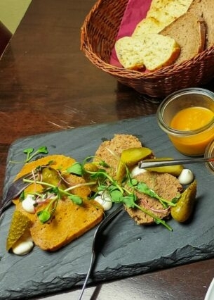 Vegane Tapas mit Dips und Brotkorb, angerichtet auf Servierplatten auf einem gedeckten Tisch