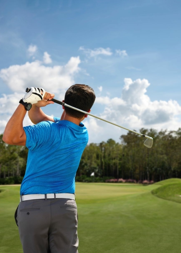 Ein Mann von hinten beim Abschlag auf einem Golfplatz