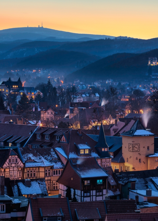 Blick auf eine beleuchtete Fachwerkstadt vor bewaldeten Hügeln