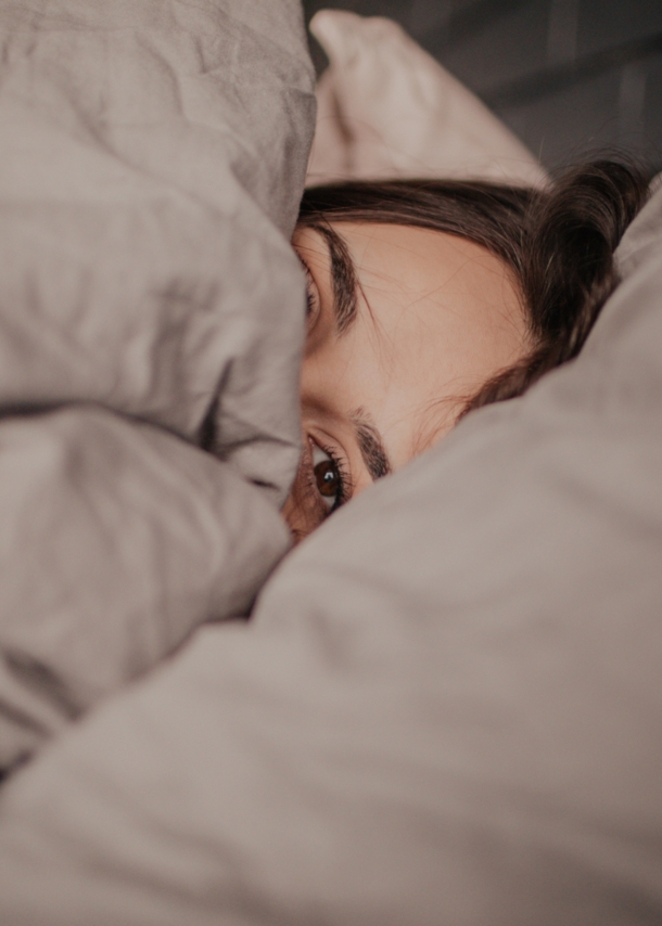 Eine Frau liegt unter einer Bettdecke im Bett