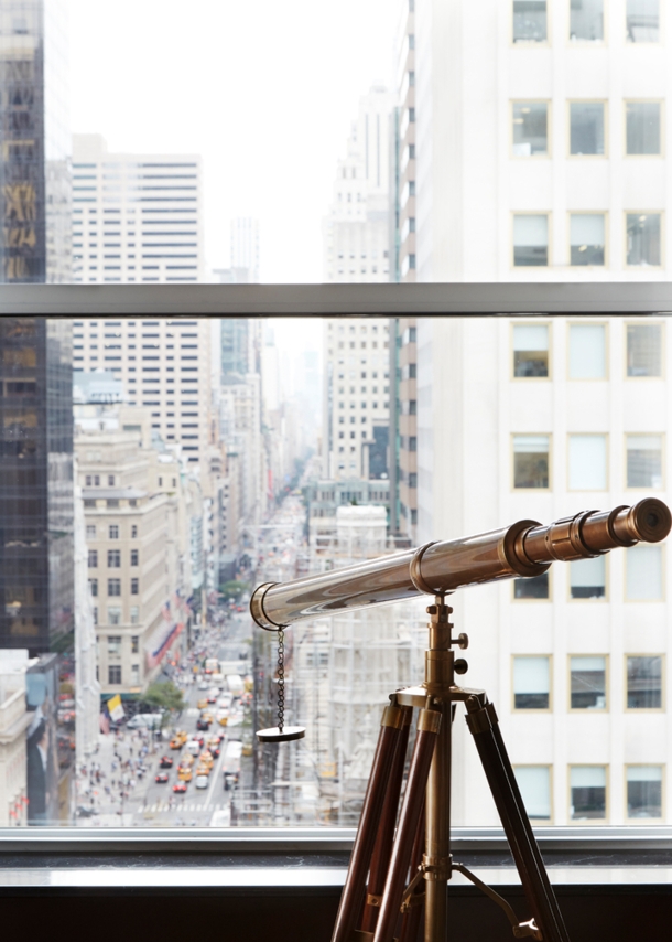 Blick durch ein Fenster auf die Fifth Avenue, am Fenster steht ein Fernrohr