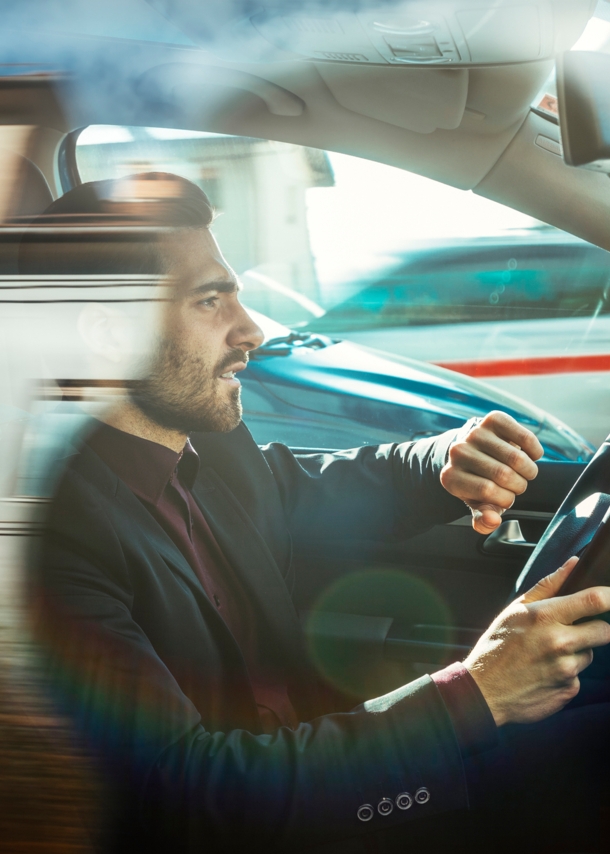 Ein Mann in einem Auto hebt seinen Arm, um auf die Armbanduhr zu schauen