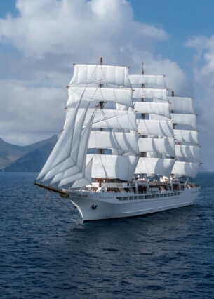 Großes Segelschiff auf dem Meer, im Hintergrund Berge