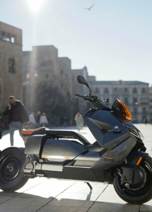 Ein grauer BMW CE 04 parkt vor Palmen in einem Fußgängerbereich.