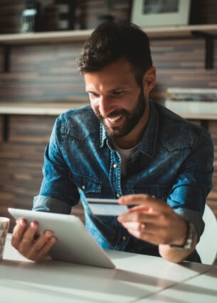 Ein lächelnder Mann am Schreibtisch beim Online-Banking