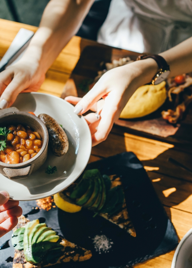 Hände reichen bei einem Brunch in Berlin eine Schale mit Essen