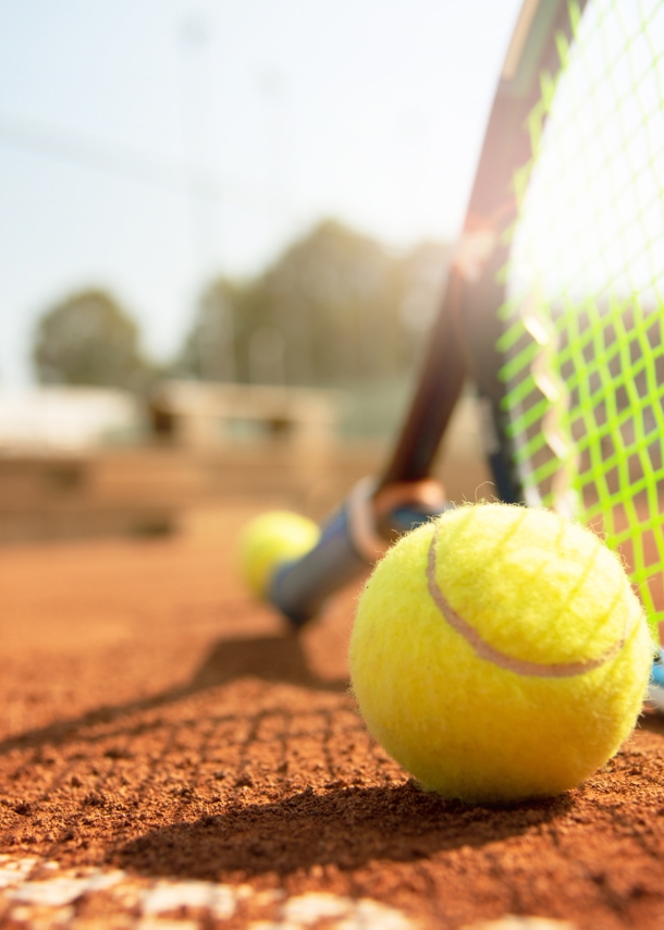 Tennisball und Schläger auf einem Tennisplatz bei schönem Wetter