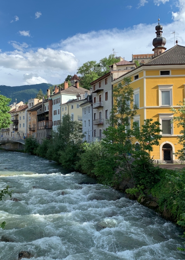 Ein Fluss verläuft inmitten von Gebäuden in Bruneck gegen den Himmel