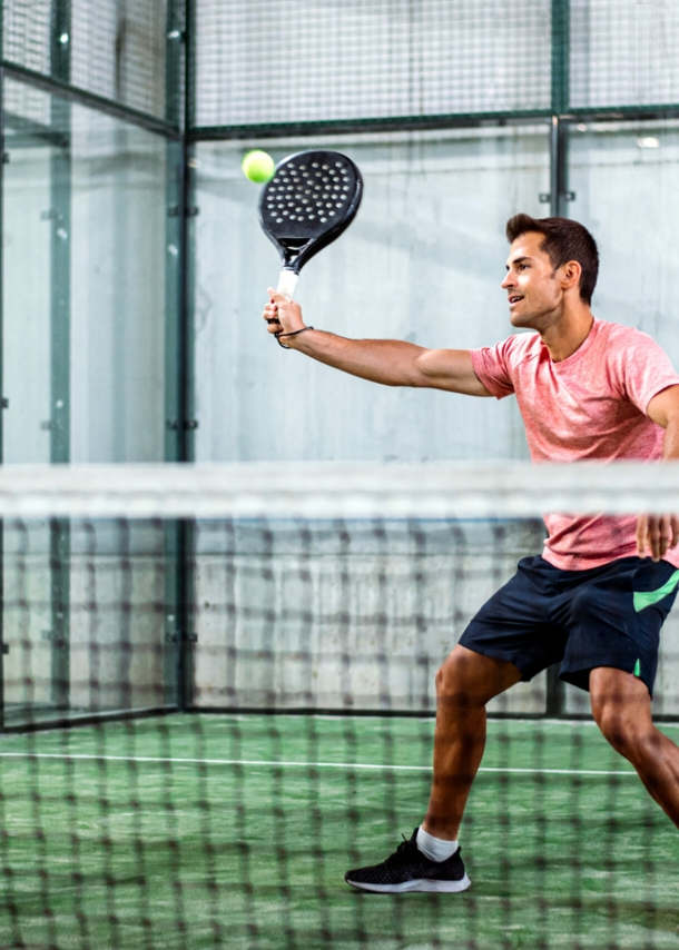 Ein Mann spielt Padel-Tennis in der Halle.