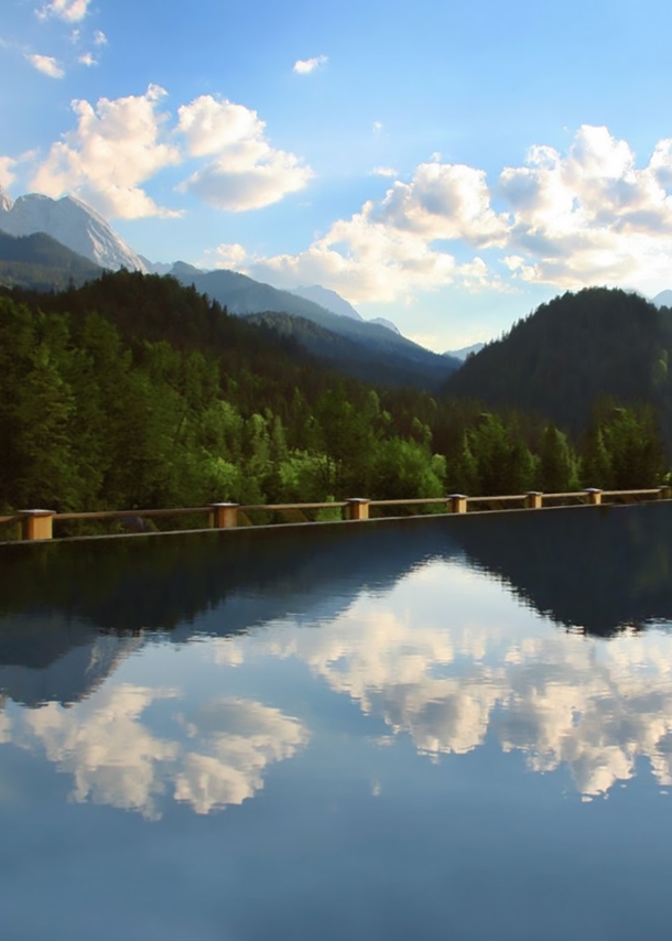 Ein großer Außenpool vor Wald- und Bergpanorama