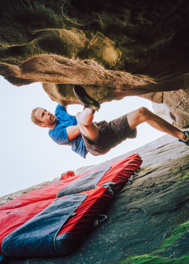 Ein Mann bouldert am Felsen, unter ihm liegt eine Matte