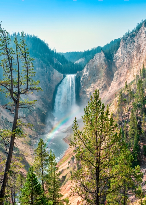 Blick auf einen Wasserfall, der in die Tiefe rauscht. Davor zeichnet sich ein kleiner Regenbogen ab.