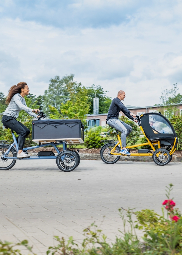 Ein Mann und eine Frau fahren auf zwei Lasten-E-Bikes