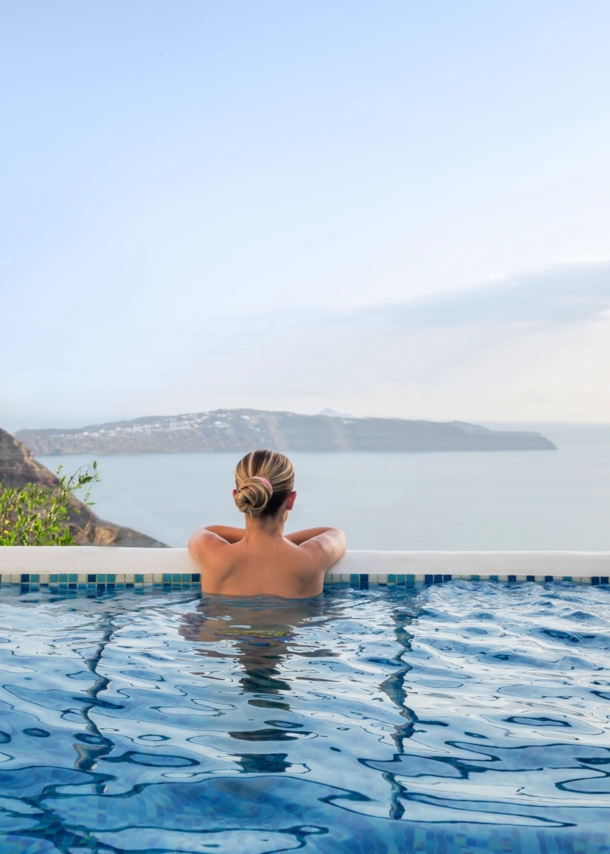 Rückansicht einer Frau in einem Infinitypool mit Blick aufs Meer