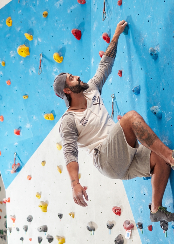 Niedriger Winkel der reifen sportlichen Kletterwand im Fitnessstudio. Die volle Länge des fitten Mannes trainiert. Er trägt Sportbekleidung.