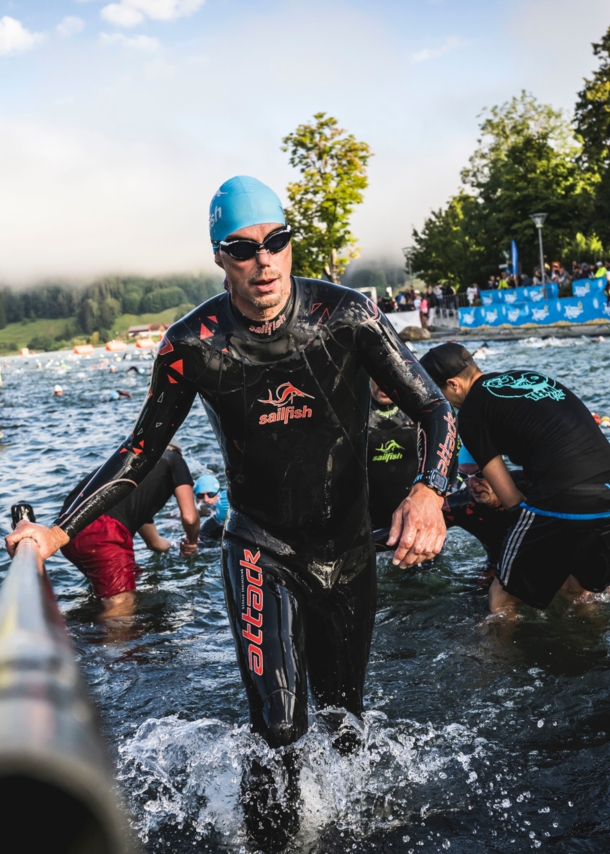 Eine Person im Neoprenanzug steigt aus einer Wasserquelle heraus